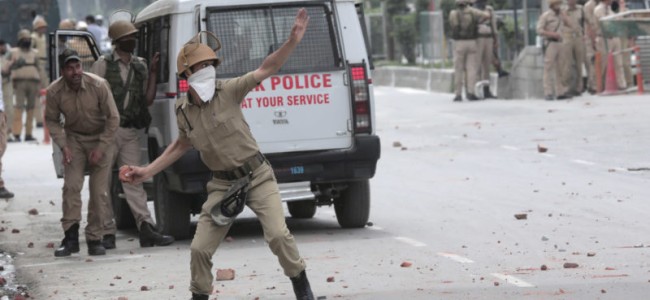 Cop pelting stones at protesting students.pic; Mudasir Khan